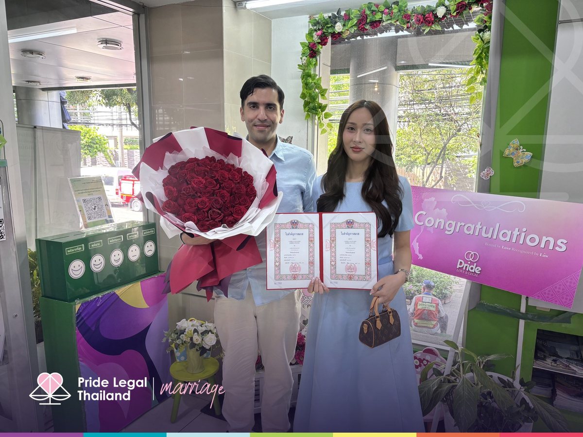 A couple with their marriage certificates and a bouquet of roses on their registration day in Bangkok