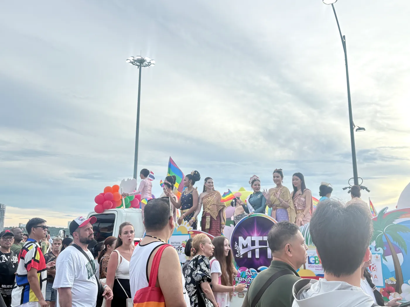 Pride parade float with performers in traditional Thai dress